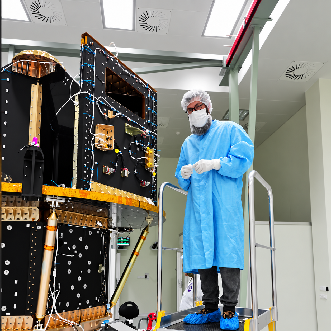 Michal Gabco in a cleanroom beside a spacecraft assembly